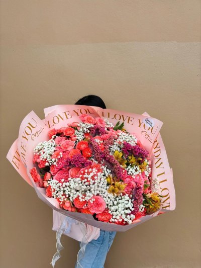 A vibrant bouquet with coral-pink roses, yellow alstroemerias, white baby’s breath, and purple celosia.