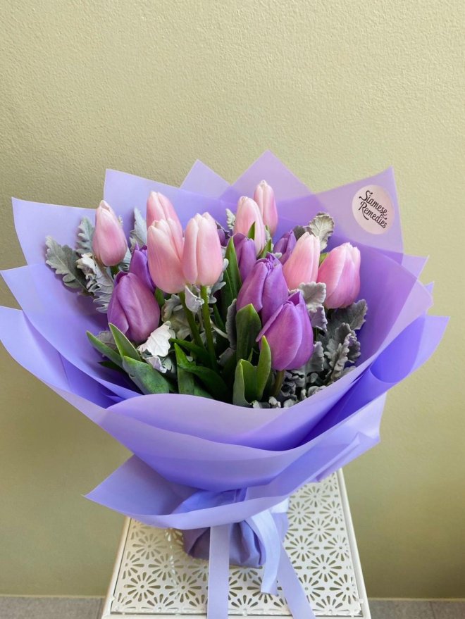 Bouquet of pink and lavender tulips with dusty miller foliage, wrapped in lilac paper with matching ribbon image