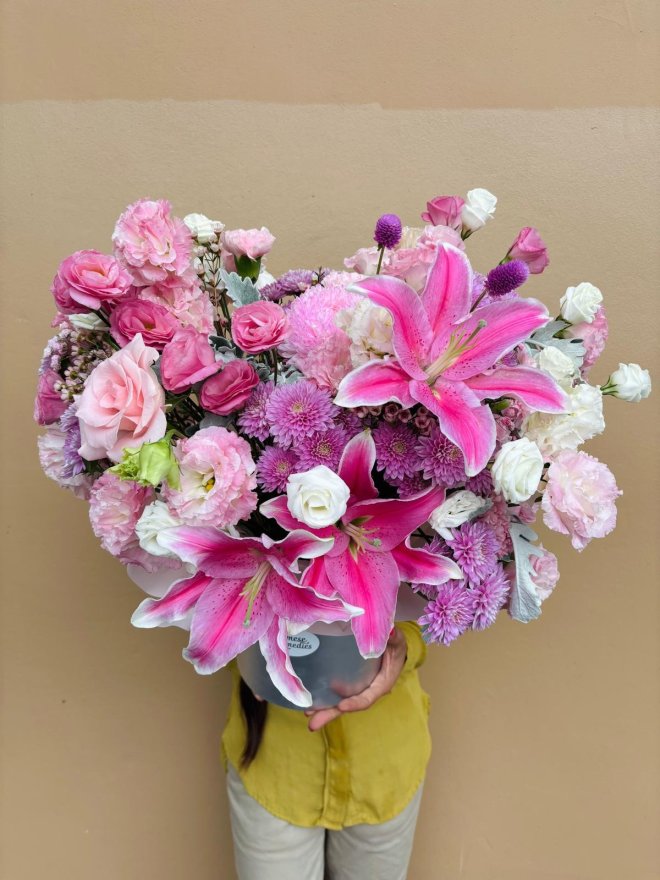 A pink hatbox bouquet of lilies, roses, lisianthuses, carnations, and chrysanthemums.