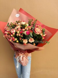 A bouquet of cream and pink-tipped roses and spray roses with eucalyptus, wrapped in terracotta and blush paper.