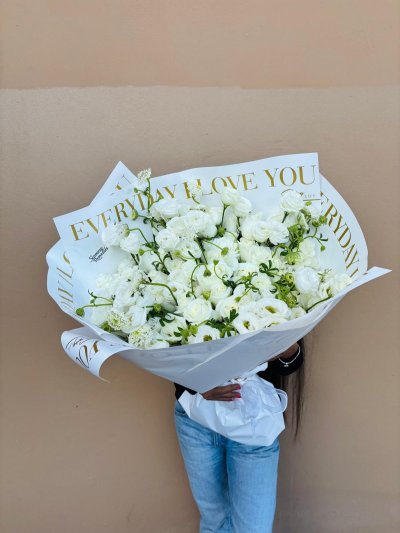 A refined bouquet of white roses and lisianthuses wrapped in “Everyday I Love You” paper.