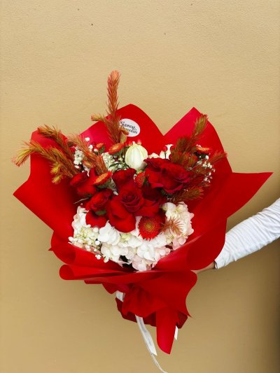 A striking bouquet with red roses, white hydrangeas, gerberas, and baby’s breath.