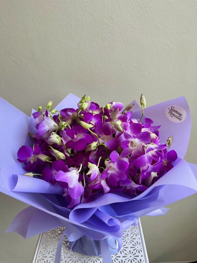 Purple dendrobium orchid bouquet wrapped in lavender paper with matching ribbon.