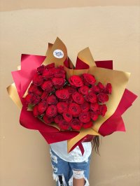 A grand bouquet of vibrant red roses wrapped in gold and red paper.