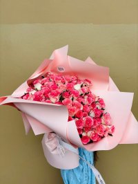 A grand bouquet of pink and white roses wrapped in soft pink paper.