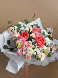 A pastel bouquet of peach roses, lisianthuses, carnations, chrysanthemums, and baby's breath wrapped in white.