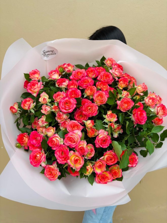 A lively bouquet of coral-pink roses with golden accents, ideal for romantic and celebratory moments.