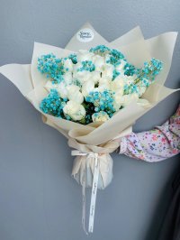 A striking bouquet of white roses paired with vibrant blue baby's breath, wrapped in cream paper and tied with a white ribbon.