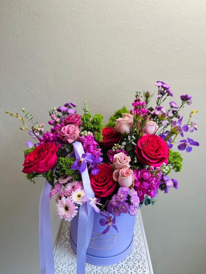 A bold floral box with red and pink roses, purple orchids, carnations, and chrysanthemums.