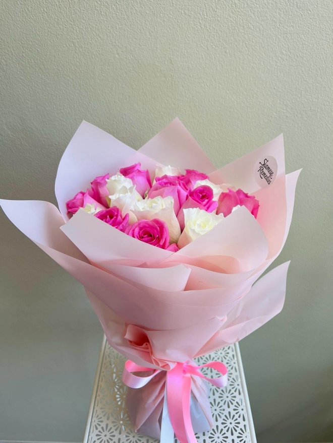 Bouquet of white and hot pink roses wrapped in blush pink paper with satin pink and white ribbons