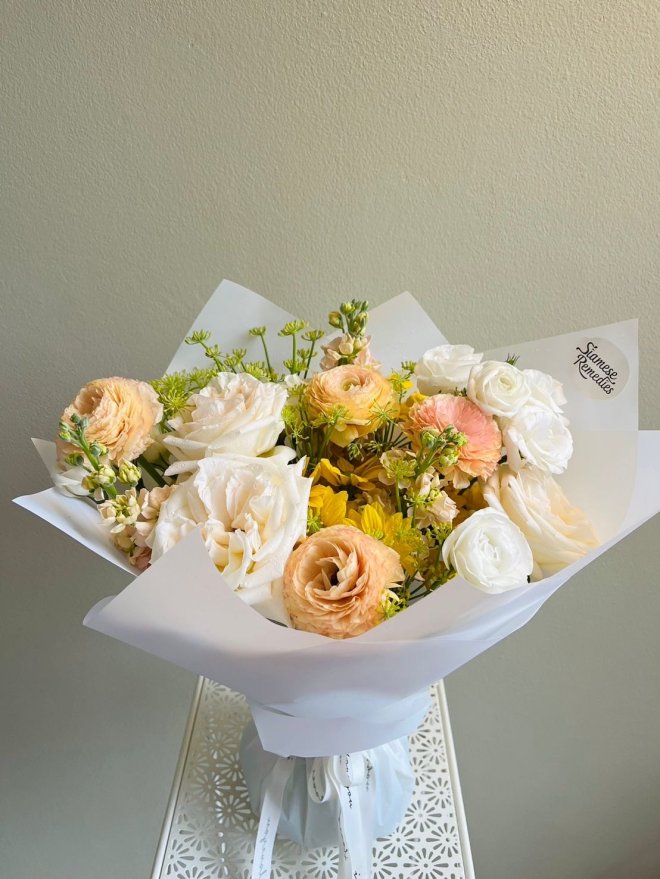 A fresh bouquet with white, yellow, and peach roses and soft floral accents.