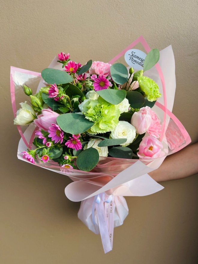 Green carnations, sweet pink tulips, white lisianthus, and playful magenta asters, accented with lush eucalyptus wrapped in delicate pink.
