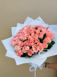 A full bouquet of soft peach roses wrapped in white, perfect for romantic occasions.