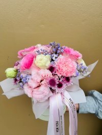 A pastel hatbox bouquet featuring pink roses, lisianthuses, carnations, and lavender baby’s breath.