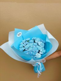 A bouquet of blue-tinted carnations wrapped in sky-blue paper.