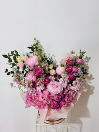 A lavish pink hatbox bouquet with peonies, roses, lisianthuses, carnations, hydrangeas, and stock flowers.