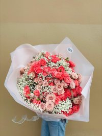 A dreamy bouquet of coral and blush roses surrounded by white baby’s breath.