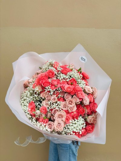 A dreamy bouquet of coral and blush roses surrounded by white baby’s breath.