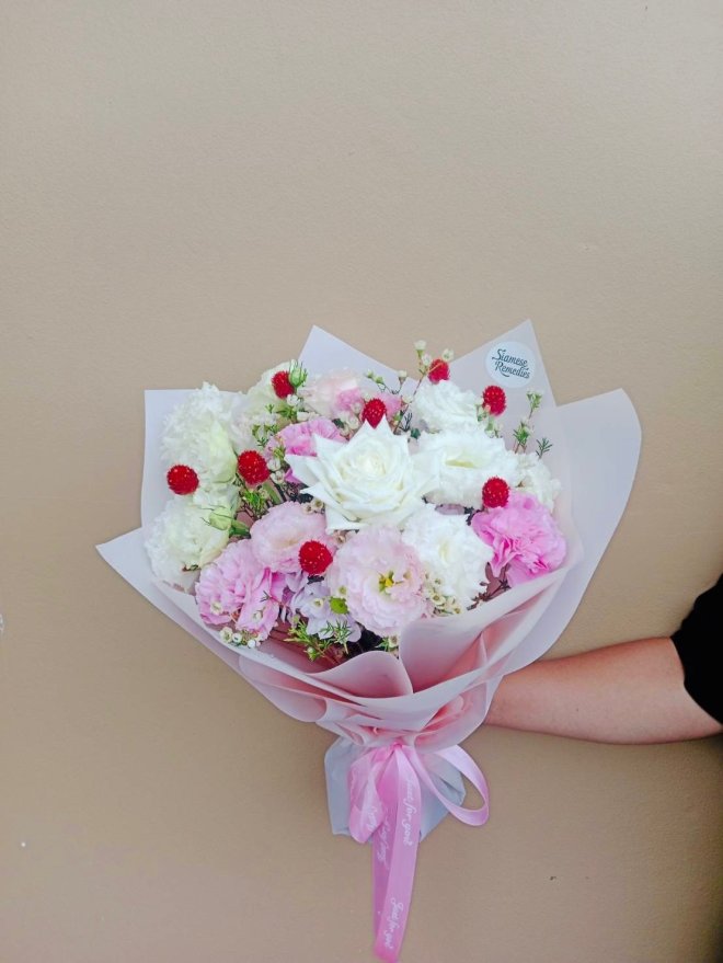 Bouquet of white roses, pink lisianthuses, white carnations, wax flowers, and red gomphrena.