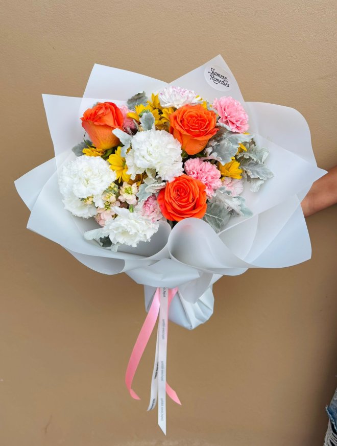 A cheerful bouquet of orange roses, yellow gerberas, white and pink carnations with silvery foliage.