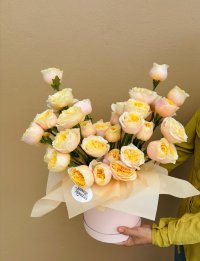 A hatbox arrangement of creamy peach and golden yellow roses.