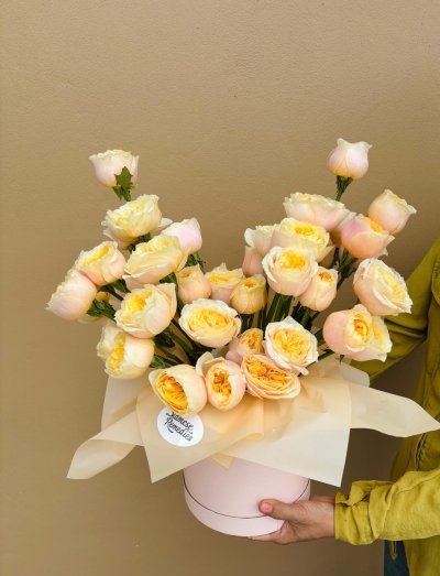 A hatbox arrangement of creamy peach and golden yellow roses.