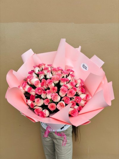 A large bouquet of pink and white roses beautifully arranged in pink wrapping.