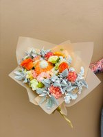 A warm bouquet featuring orange roses, peach carnations, green lisianthus, and silver leaves.
