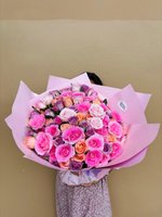 A vibrant bouquet featuring pink, peach, purple, and cream roses arranged in a romantic style.