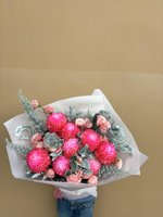 Bouquet with bright pink flowers and soft pink roses wrapped in white paper.
