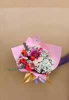 Pink and coral flower bouquet with lilies, roses, carnations, and baby’s breath wrapped in pink and gold paper.