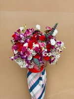 A hatbox arrangement of red roses, purple orchids, white lisianthus, carnations, and baby’s breath.