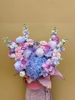 Czarina bouquet featuring blue hydrangeas, pink roses, lilac orchids, and delphiniums in pastel tones.