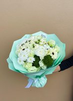 Pure Serenity bouquet held in hand, featuring white gerberas, white roses, light green lisianthus, and white chrysanthemums wrapped in mint green p...
