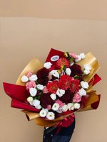 Red and white flower bouquet with dahlias, lisianthus, and carnations wrapped in red and gold paper.