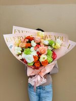 A vibrant bouquet of pink, white, and purple roses, lilies, and orchids with decorative wrapping.