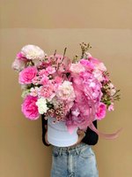 Pink and white flower arrangement with roses, hydrangeas, and carnations in a white hat box with a pink ribbon.