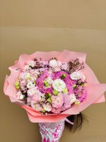 Pink flower bouquet with dahlias, lisianthus, and carnations wrapped in soft pink paper.