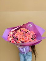 A luxurious bouquet featuring pink, peach, lilac, and cream roses wrapped in soft lavender paper.