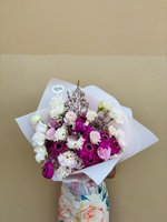 Pandora bouquet featuring purple and magenta gerberas, white and pink carnations, pink and white lisianthus, and baby's breath, wrapped in white pa...
