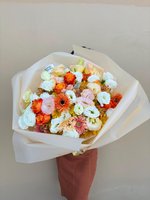 Romantic pink and green flower bouquet with roses, lisianthus, and carnations wrapped in soft white paper.