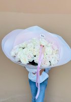 Large luxury bouquet of 25 white and pale pink roses wrapped in soft blue and pink tissue paper with pink ribbon, held by person in white top and j...