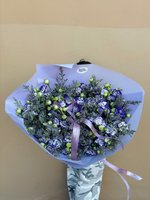 Hand-tied bouquet of blue and white roses with green foliage, wrapped in purple paper and tied with ribbon