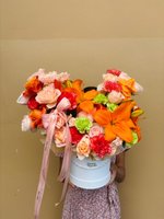 Vibrant Flame bouquet with orange lilies, coral roses, red carnations, and peach flowers in a white box.