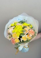 Bouquet with peach roses, yellow chrysanthemums, and greenery wrapped in white paper