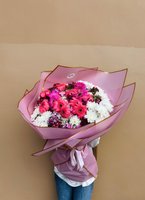 Large bouquet of pink gerberas, white chrysanthemums, and magenta fillers wrapped in blush paper with golden trim.