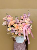 Celeste bouquet with peach and blush roses, pastel stock flowers, and soft pink ribbon in a white hatbox.
