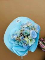 Sapphire bouquet featuring blue and light blue lisianthus flowers, white roses, and baby's breath wrapped in soft blue paper
