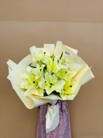 Celestial Lily bouquet with glowing yellow-white lilies wrapped in soft cream paper.