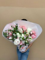 Person holding Girlfriend bouquet with white roses, pink lisianthus, pink carnations and spotted alstroemeria wrapped in translucent paper